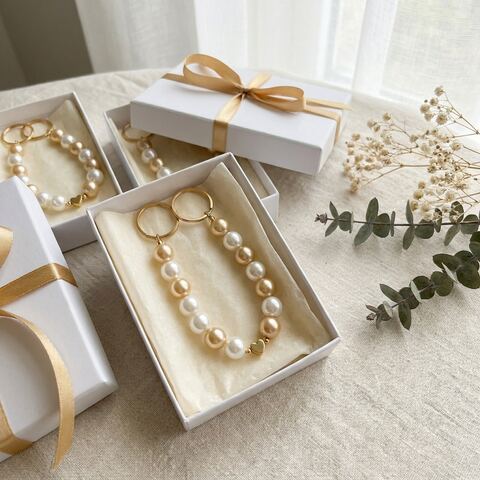 ของชำร่วยงานแต่งโทนขาว-ทอง — พวงกุญแจลูกปัดพร้อมชาร์มหัวใจ ในกล่องผูกริบบิ้นทอง